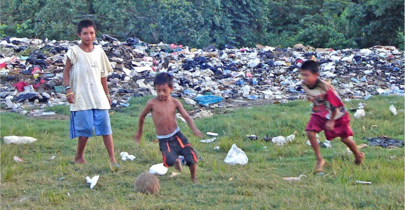 Children playing in trash-ridden field